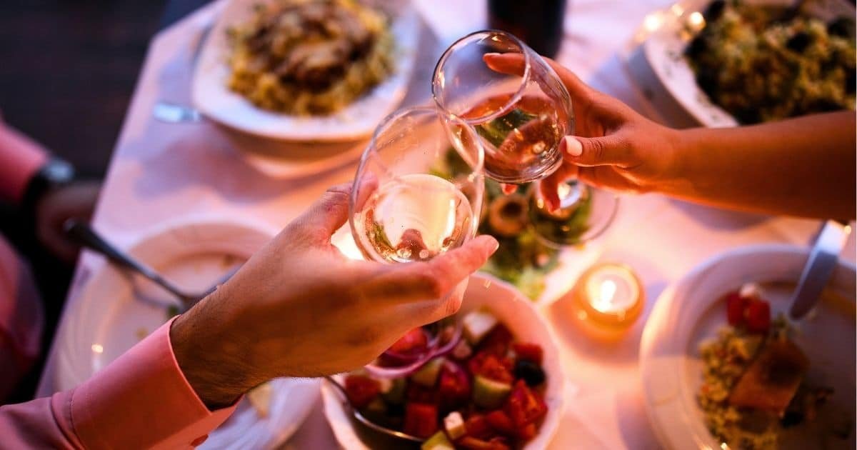 Couple toasting wine glasses at an upscale dinner table. Chicago is a great place for a date.